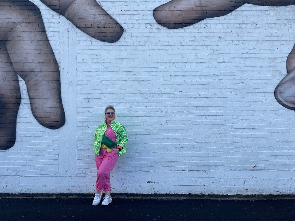 Woman standing against brick wall in bright pink and yellow 